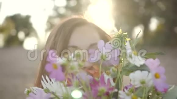 美丽的年轻女子微笑着拿着一束野花的肖像视频的预览图