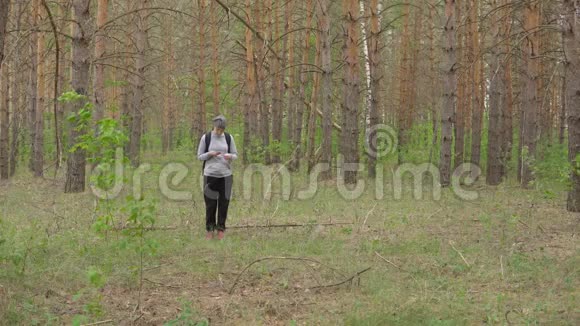 带着背包的女人穿过森林正面观点视频的预览图