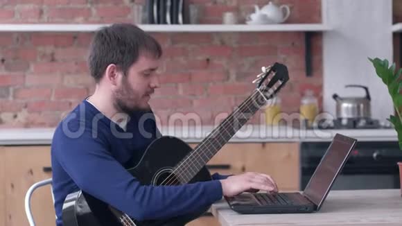 快乐的音乐人学习弹吉他使用笔记本电脑在线视频教学享受音乐视频的预览图