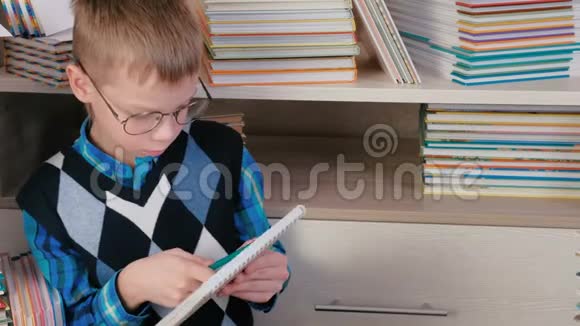 七岁的男孩戴着眼镜坐在书中的素描书里写着一些东西视频的预览图