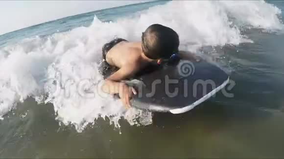 男孩正拿着一块木板在海浪上游泳视频的预览图