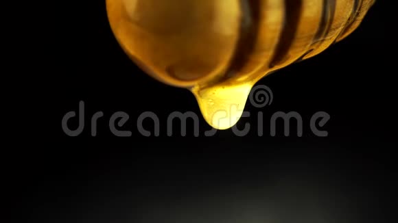 浓蜜滴在黑色背景上的蜂蜜勺子上特写视频的预览图