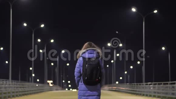 一个穿着冬衣的女孩穿过一个荒芜的夜城视频的预览图