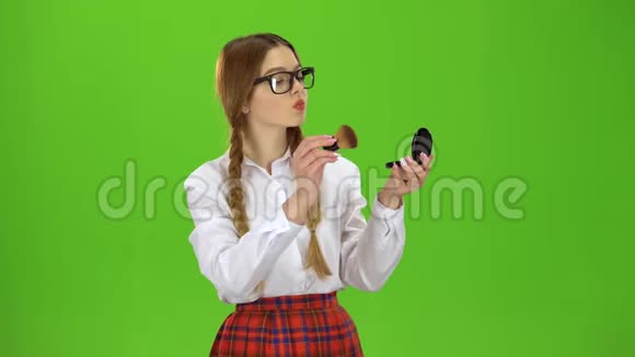 戴眼镜的女学生用刷子把鼻子涂成粉末绿色屏幕视频的预览图
