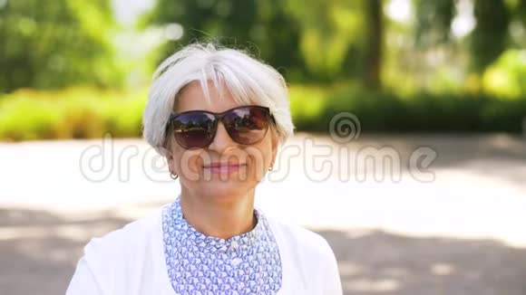 在夏季公园摘墨镜的老妇人视频的预览图
