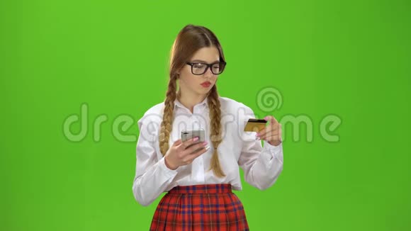 戴眼镜的女孩用金卡在电话上拨号码绿色屏幕视频的预览图