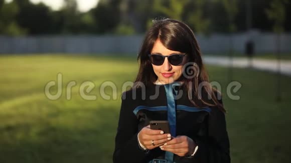 戴太阳镜的年轻女性使用智能手机视频的预览图