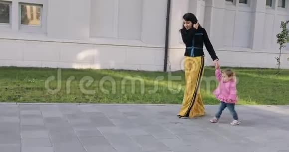 布鲁内特时尚的年轻女性与小女孩在城市公园散步视频的预览图