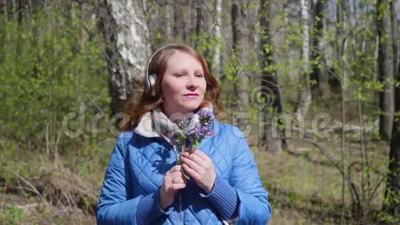 公园里的一个年轻女孩戴着耳机听音乐戴着耳机欣赏音乐的女人视频的预览图