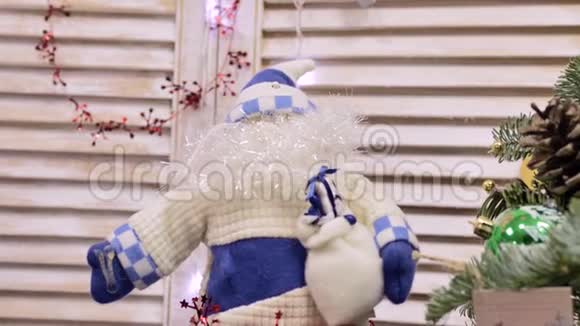 蓝白相间的圣诞老人娃娃有着浓密的胡须和帽子坐在壁炉上视频的预览图