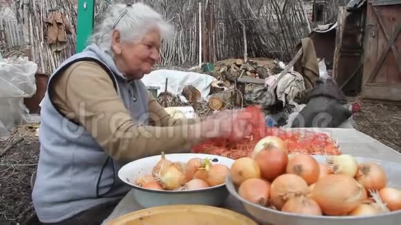 一位白发苍苍的老妇人在厨房做饭前拿起洋葱有机蔬菜和自己的作物视频的预览图