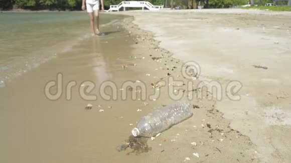年轻女孩在沙滩上收集垃圾塑料瓶在海滩上收集志愿者清洁海滩视频的预览图