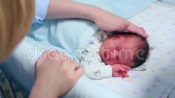 一个刚出生的婴儿在婴儿床上哭泣母亲试图安慰他视频的预览图