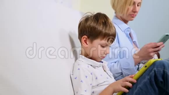 一家三口坐在沙发上使用数字设备那个男孩用平板电脑和母亲浏览关于视频的预览图
