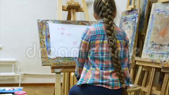 小女孩艺术家在画架上画画绘制过程画笔和画布的特写视频的预览图