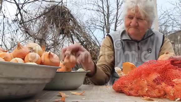 一位白发苍苍的老妇人在厨房做饭前拿起洋葱有机蔬菜和自己的作物视频的预览图