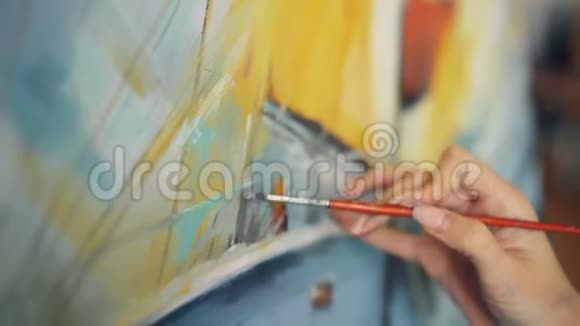 特写镜头女性手握画笔用鲜艳的油画颜料在画布上描绘美丽的画面视频的预览图