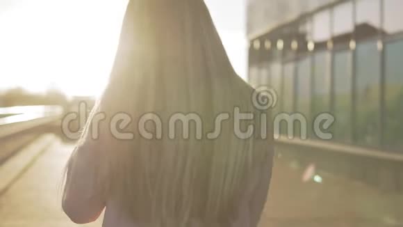 美丽的金发女郎对着镜头微笑日落时转身视频的预览图