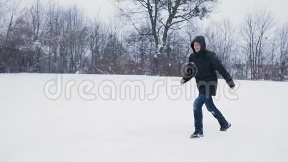 布鲁内特年轻人穿着黑色引擎盖享受降雪有趣的舞蹈雪中央公园降雪慢动作视频的预览图