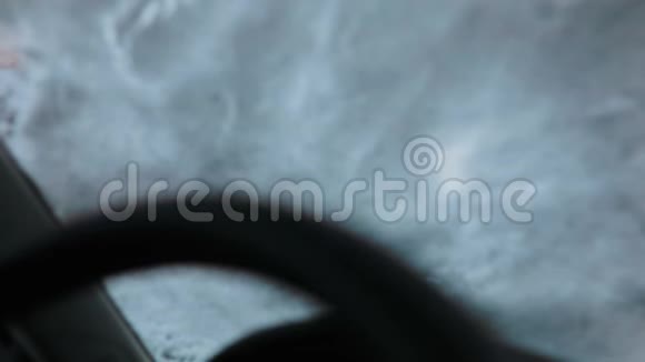 穿着黑色引擎盖的布鲁内特年轻人从雪地上清洁汽车的挡风玻璃内景视频的预览图