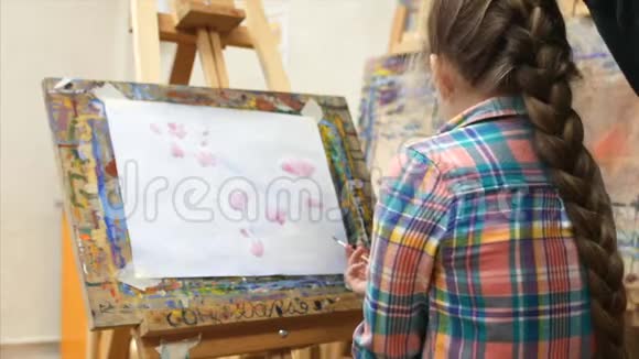 小女孩艺术家在画架上画画绘制过程画笔和画布的特写视频的预览图