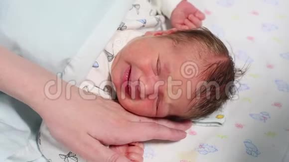 一个刚出生的婴儿在婴儿床上哭泣母亲试图安慰他视频的预览图