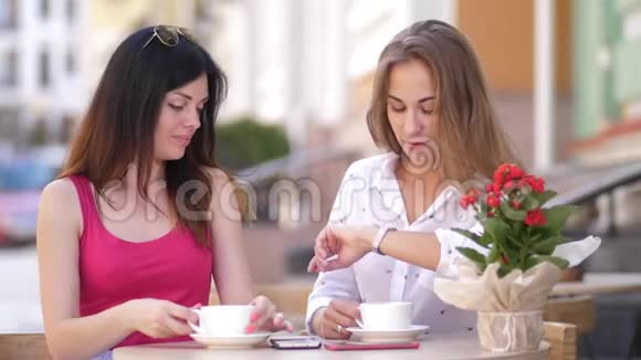 两个漂亮的年轻女人坐在咖啡馆的桌子旁聊天4k慢动作视频的预览图