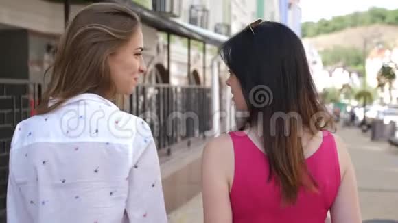 后景两个漂亮的女人在成功地用纸袋和慢动作购物后上街视频的预览图