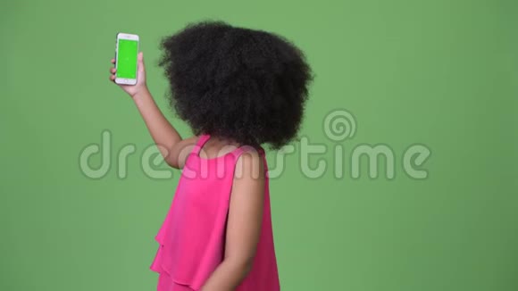 年轻可爱的非洲女孩留着非洲头发带着手机和手指视频的预览图
