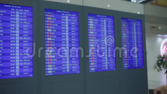 慢动作快乐的亚洲女人看着信息板用行李在候机大厅检查她的航班视频的预览图