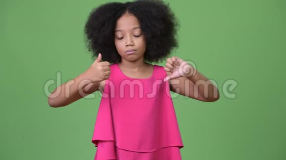 一个年轻的头发凌乱的非洲女孩在竖起大拇指或竖起大拇指之间做出选择视频的预览图