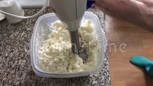 一个女人在装有干酪的容器里加入酸奶油准备奶酪甜点视频的预览图