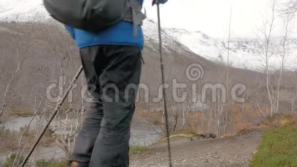 一个人穿过一个美丽的公园带着背包和特殊的棍子为斯堪的纳维亚人散步他领导一个视频的预览图