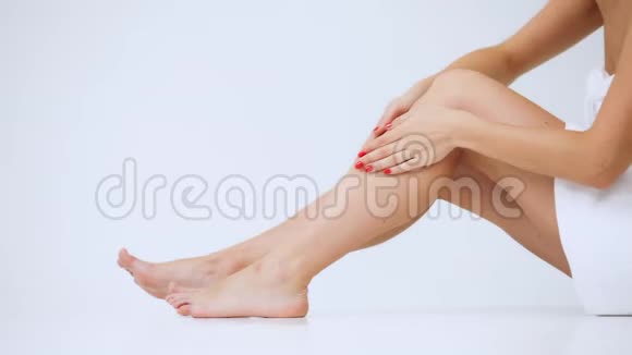 特写的女人她的腿女孩抚摸她的腿与清爽的奶油在她的腿上隔离在白色的背景视频的预览图