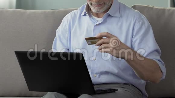 高级男性可在电脑上输入信用卡号码网上支付购物视频的预览图