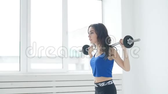 健身运动训练和生活方式概念白色室内健身房中有杠铃肌肉的年轻妇女视频的预览图