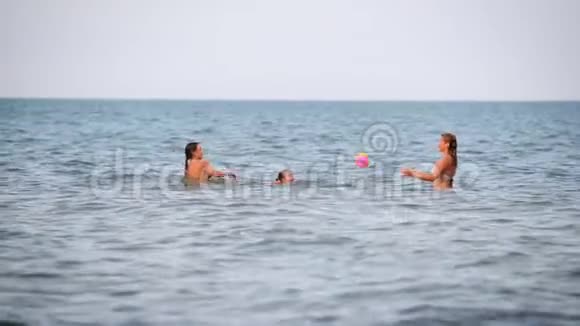 快乐的女人带着孩子在水上冲浪时玩球视频的预览图