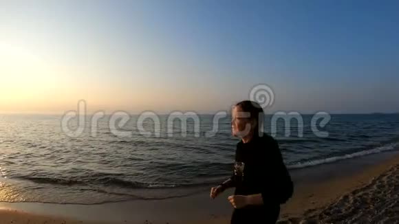 日落时分在沙滩上慢跑的女跑步者视频的预览图