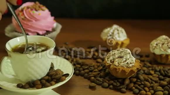 白色杯子里的咖啡女人用勺子蛋糕和桌上散落的咖啡豆搅拌着视频的预览图