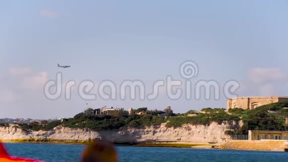 从船上看到的岩石海岸绿色的苔藓和灌木一个蓄水池和一架飞机在天空中飞行海洋视频的预览图