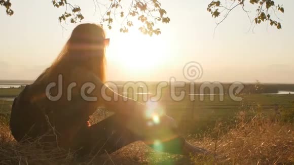 脸廓年轻女孩走在田野里欣赏日落一个女人戴着太阳镜看太阳概念徒步旅行视频的预览图
