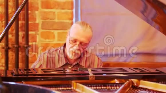 一个头发花白的人头上有一条尾巴戴着眼镜热情而体贴地用爵士乐弹钢琴视频的预览图