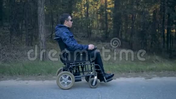 一个残疾人坐着电动轮椅在路上行走的侧视图视频的预览图