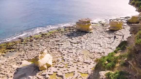 两名游客正沿着一个不寻常的岩石海岸走着那里有石头和岩石看着周围的一切旅费视频的预览图