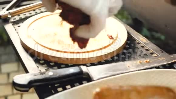 厨师把现成的排骨从切割板转移到一个盘子里里面有酱汁和香肠视频的预览图