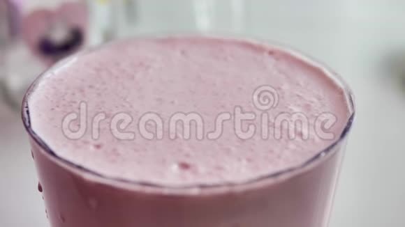 透明玻璃中的粉红色奶昔气泡破裂特写自然光视频的预览图
