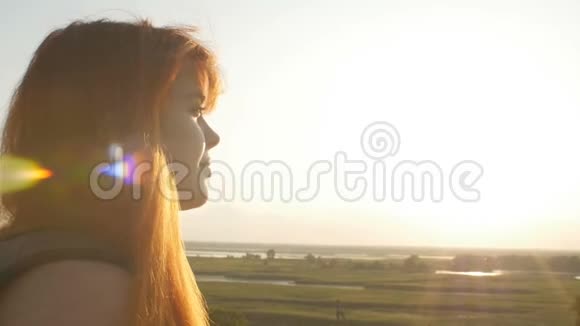 脸廓年轻女孩走在田野里欣赏日落一个女人戴着太阳镜看太阳概念徒步旅行视频的预览图