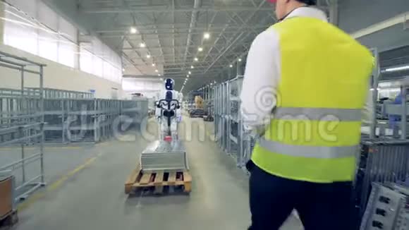 男厂工人正在发射一个机器人开始拉动运输小车视频的预览图