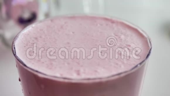 透明玻璃中的粉红色奶昔气泡破裂特写自然光视频的预览图