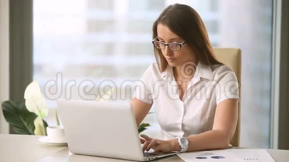 年轻的女商人戴着眼镜厌倦了在笔记本电脑上工作视频的预览图